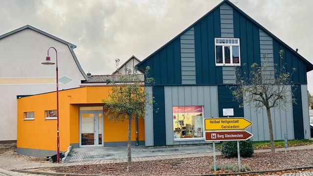 Ein modernes Haus mit blauer Fassade und orangefarbenem Anbau sowie Straßenschildern