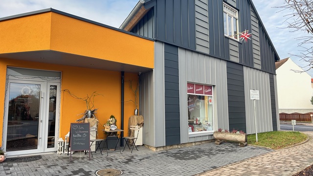 Ein modernes Gebäude in Grau und Orange mit Dekoration vor dem Eingang und Schaufenstern